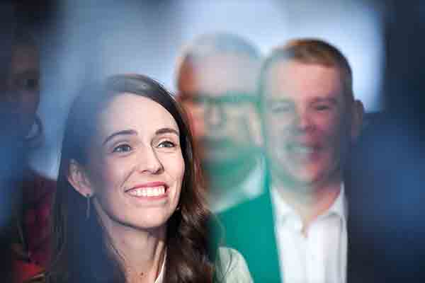 Jacinda Ardern smiling whist surrounded by her Labour Party colleagues.