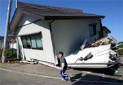 A boy walks by a collapsed house in Ojiya, about 260 kilometres northwest of Tokyo, on 23 October.
