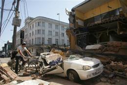 A man rides his bicycle along a destroyed building in Concepcion,  Chile, Saturday Feb. 27, 2010 after an 8.8-magnitude struck central  Chile.