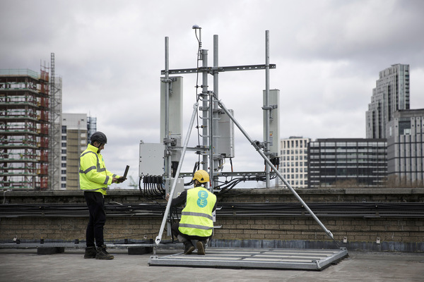Communication workers install equipment on a London rooftop.