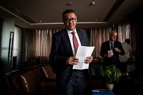 Tedros Adhanom Ghebreyesus photographed in a conference room holding a piece of paper