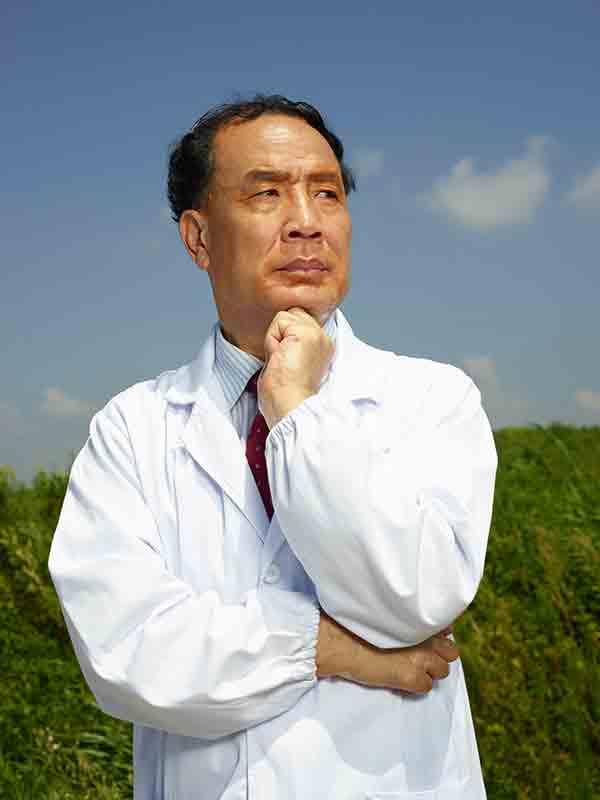 Portrait of Zhang Yongzhen in a white lab coat against green vegetation and blue sky.