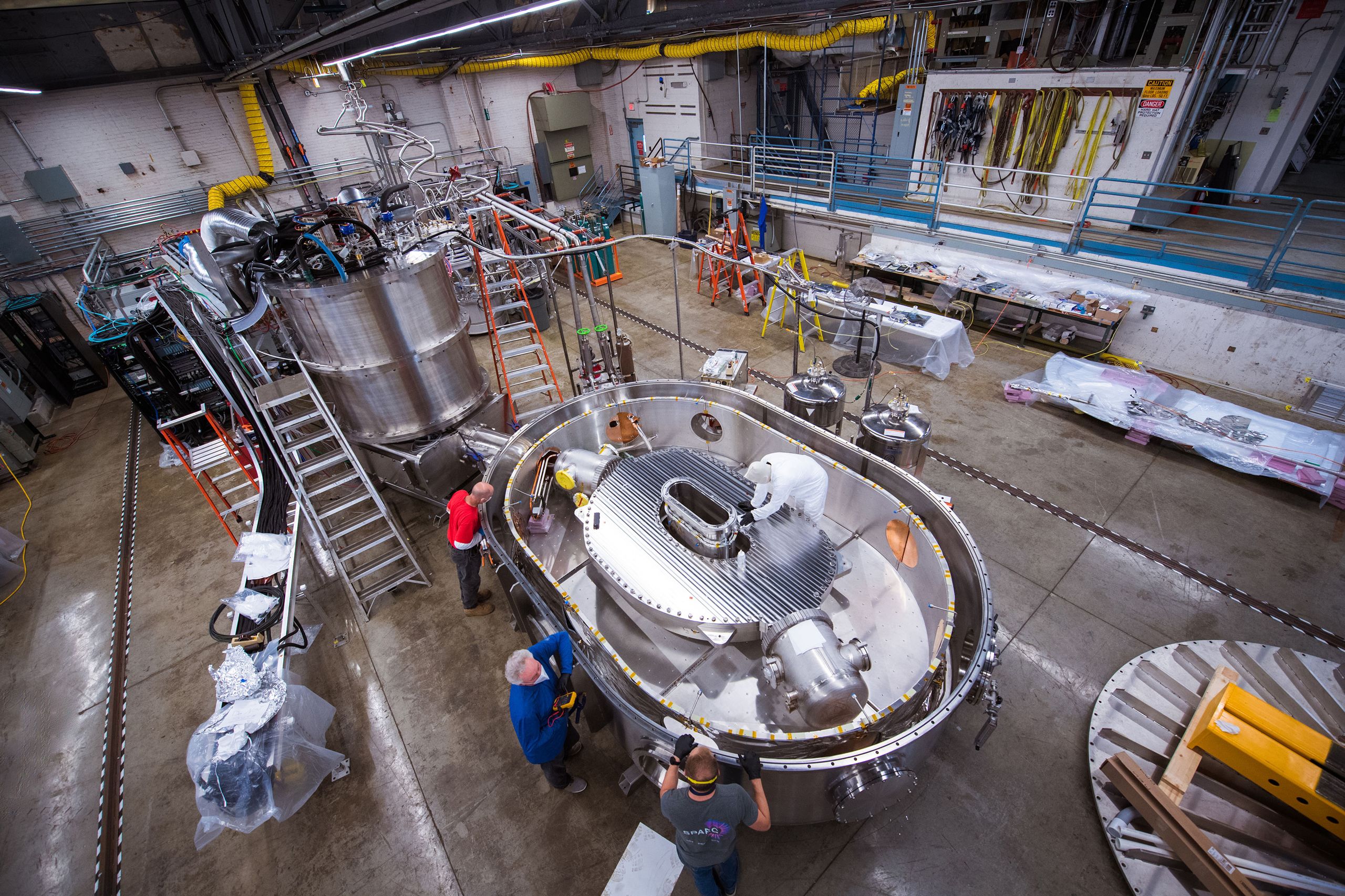 Aerial view of people working on a large-bore, full-scale high-temperature superconducting magnet designed and built by Commonwealth Fusion Systems and MIT’s Plasma Science and Fusion Center