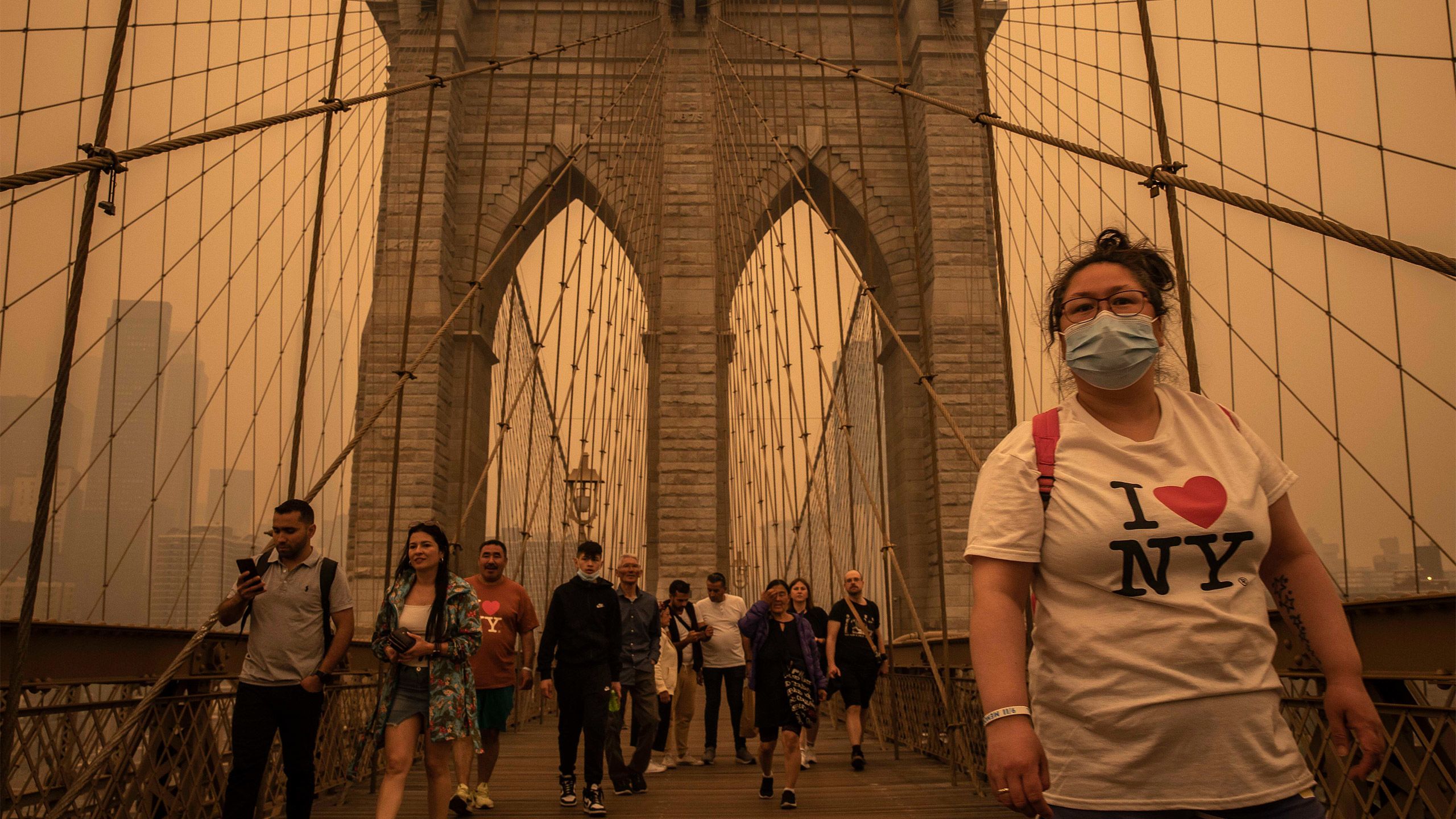 Pessoas cruzam a ponte do Brooklyn em meio a uma densa neblina causada pela fumaça do incêndio florestal no Canadá em Nova York, 7 de junho de 2023