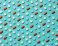 Abstract pattern of pills (red oblongs, white circles and blue circles) on a pale blue background.