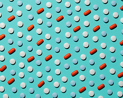 浅蓝色背景上的药丸（红色长方形、白色圆圈和蓝色圆圈）的抽象图案。